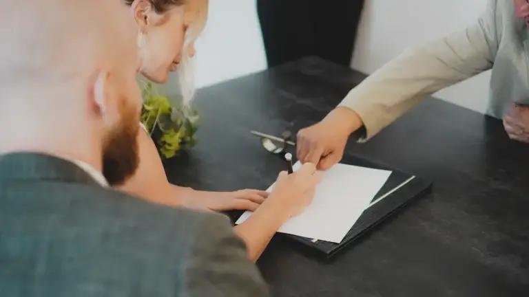 Duas pessoas a assinar um documento numa mesa