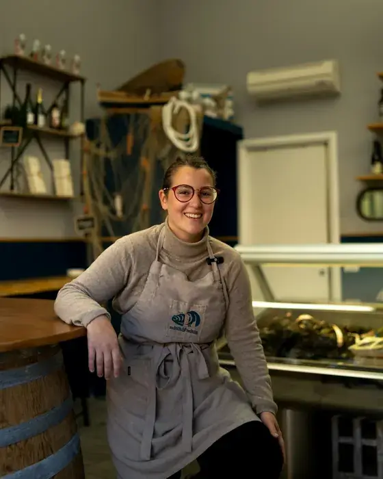 Dona de uma mercearia sorridente ao balcão